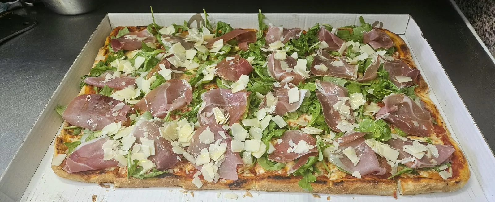 Blechpizza mit Parmaschinken, Rucola und Grana